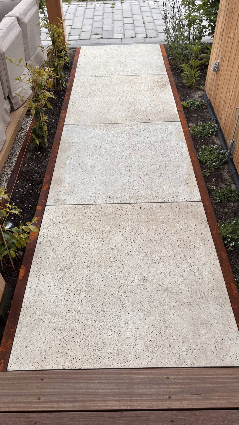 Strak bestraat pad met borderbeplanting richting de berging