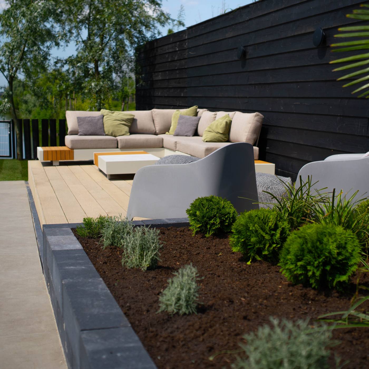 Vlonderterras met loungeset en verhoogde border met beplanting