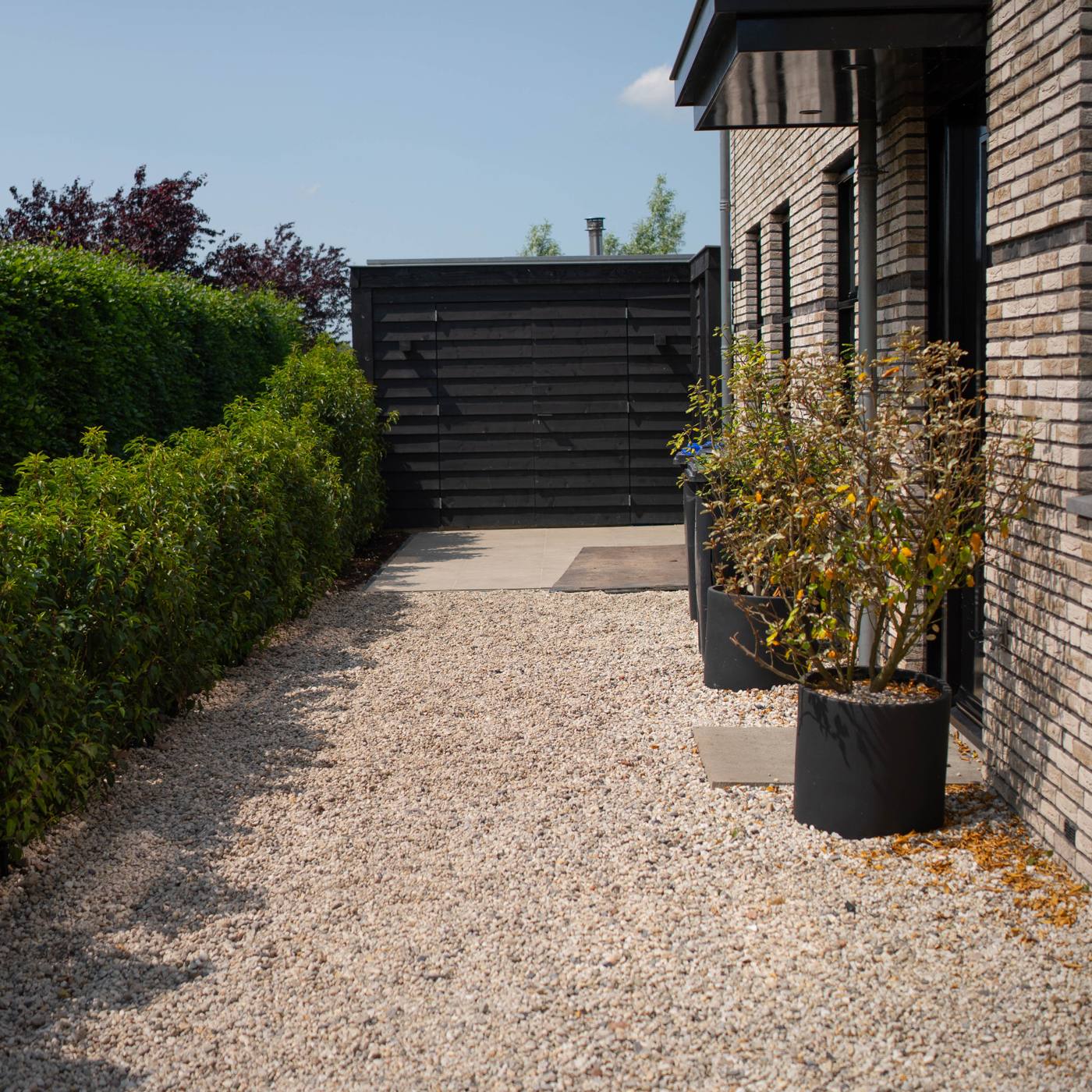 Grindpad met haag langs de moderne woning